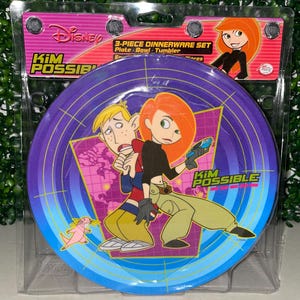 May include: A 3-piece Disney Kim Possible dinnerware set. The plate features Kim Possible and Ron Stoppable in a dynamic pose against a purple and blue background. The set includes a plate, bowl, and tumbler.