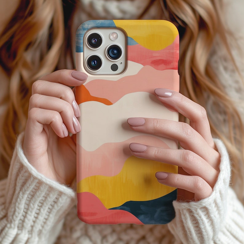 a woman holding up a phone case with a colorful design