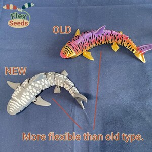 May include: Two flexible shark toys, one gray with white spots labeled "NEW" and one purple and orange labeled "OLD". The caption reads "More flexible than old type."