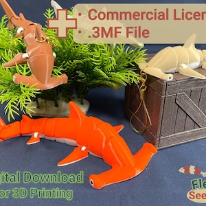 May include: Three 3D printed hammerhead shark models, one orange, one brown, and one beige, are displayed on a wooden crate. The orange shark is articulated and has white accents. The brown and beige sharks are posed on the crate. The image includes the text "Commercial License", ".3MF File", "Digital Download", and "For 3D Printing".