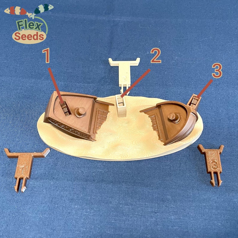 May include: A brown plastic model of a sunken ship with three separate pieces. The pieces are numbered 1, 2, and 3. The pieces are on a tan oval base.