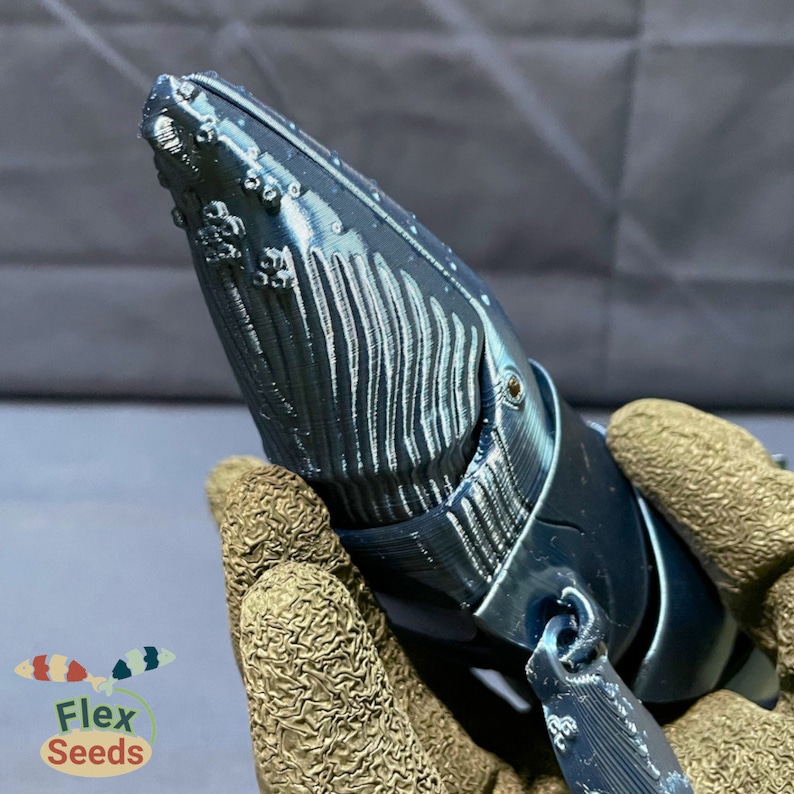 Puede incluir: Una escultura de ballena azul impresa en 3D con una superficie texturizada detallada. La ballena est&aacute; posada con la cabeza inclinada hacia arriba y la boca ligeramente abierta.