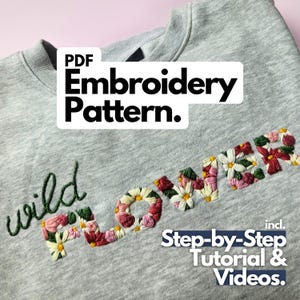 Könnte beinhalten: Ein graues Sweatshirt mit den Worten "wild flower" in bunten Fäden gestickt. Das Wort "flower" ist mit floralen Designs gefüllt. Das Bild enthält den Text "PDF Embroidery Pattern" und "Step-by-Step Tutorial & Videos."