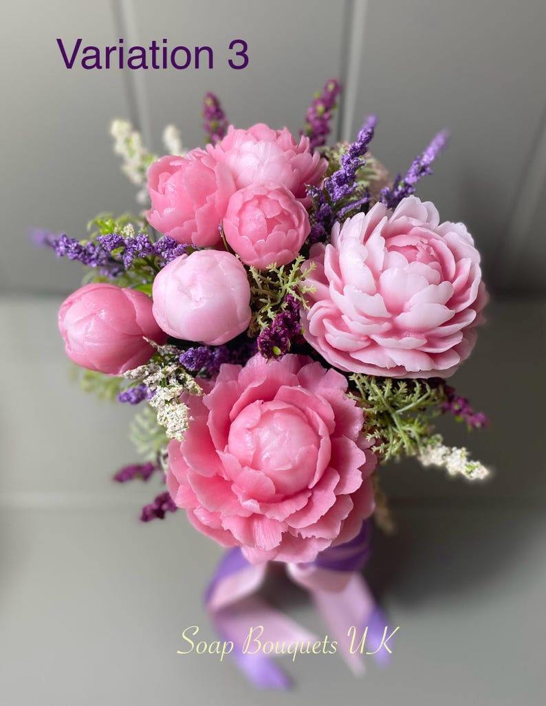 May include: A bouquet of pink soap flowers with lavender accents. The bouquet is tied with a purple ribbon and the text "Soap Bouquets UK" is visible at the bottom of the image.