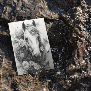 May include: A black and white pencil drawing of a white horse's head with flowers and butterflies surrounding it.