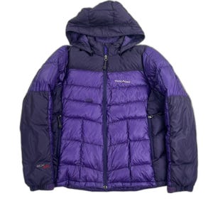 May include: A purple and dark purple hooded puffer jacket with a front zipper closure. The jacket features a quilted design, long sleeves with adjustable cuffs, and the text mont-bell printed on the chest, with EX 800 printed on the sleeve.