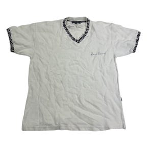 Könnte beinhalten: Weißes V-Ausschnitt-T-Shirt mit schwarzem geometrischen Besatz an Kragen und Ärmeln. Das Shirt trägt die Unterschrift von Gianni Versace in schwarzer Schrift auf der Brust. Das Versace-Logo ist ebenfalls sichtbar.
