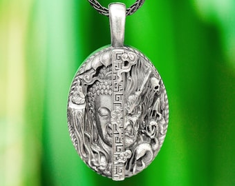 May include: Silver pendant necklace featuring a detailed, ornate design of a Buddha's face and a stylized floral pattern. The pendant is suspended from a silver chain.