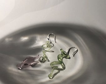 Op de afbeelding: Een paar oorringen met een spiraalvormig ontwerp. De ene oorring is lichtgroen en de andere is lichtpaars.