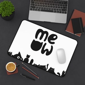 Op de afbeelding: Een witte rechthoekige muismat met een zwarte rand. De muismat heeft het woord "meow" in een speels lettertype, waarbij de "o" is vervangen door een katten silhouet. Een rij zwarte katten silhouetten omzoomt de onderrand.