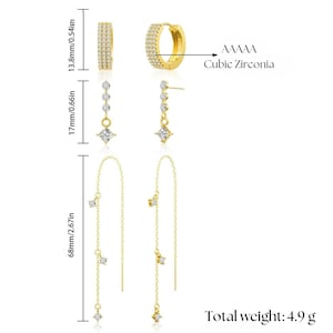 May include: A set of three pairs of gold earrings with cubic zirconia stones. The earrings include a pair of hoops, a pair of drop earrings, and a pair of long chain earrings.