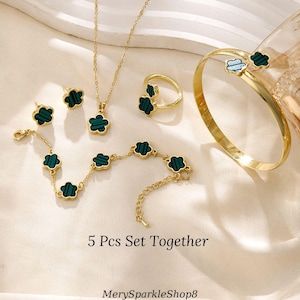 May include: A 5-piece jewelry set featuring a gold necklace, bracelet, ring, and earrings. Each piece has a green clover-shaped pendant with a gold border.