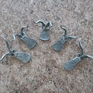 以下が含まれることがあります： 角のあるスタイリッシュな動物の頭を模した、銀色の金属製のチャームが6つ。チャームは素朴で手作り感のある仕上がりです。