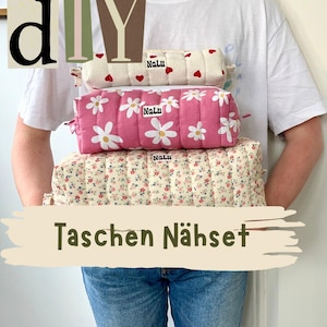 Könnte beinhalten: Ein Stapel von drei gesteppten Stoffbeuteln mit verschiedenen Mustern. Der obere Beutel ist cremefarben mit roten Herzen, der mittlere ist rosa mit weißen Gänseblümchen und der untere hat ein Blumenmuster. Auf jedem Beutel steht das Wort "Nalu".