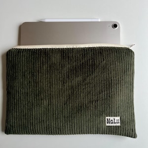 May include: Dark olive green corduroy tablet case with a cream zip and a small white label reading "Nalu." A silver tablet and white stylus are visible. The case is designed to protect and carry a tablet, ideal for travel or everyday use.
