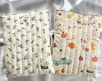 Peut inclure: Deux housses rectangulaires en tissu matelassé avec fermeture à bouton. La housse de gauche présente un motif de petites feuilles brunes sur fond crème. Celle de droite affiche un imprimé automnal avec citrouilles, écureuils et camion. Étiquette Nalu.