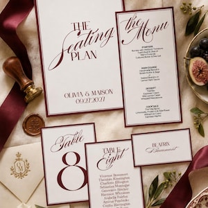 May include: A wedding stationery set featuring a seating plan, menu, table number cards, and a place card with deep burgundy text and borders on white paper. The text includes The Seating Plan, The Menu, Table 8, and the name Beatrix Beaumont.