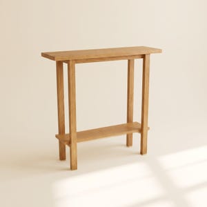 Op de afbeelding: Een lichtbruine houten sidetable met een rechthoekig bovenblad, vier rechte verticale poten en een enkele onderste plank die tussen de poten is geplaatst. Het meubelstuk is gemaakt van natuurlijk hout met een zichtbare houtnerf.