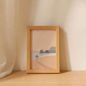 Peut inclure: Une impression d'art encadrée représentant une scène de plage minimaliste. L'impression présente une personne marchant vers la mer, avec une palette de couleurs pêche, grise et beige. Le cadre est en bois clair.