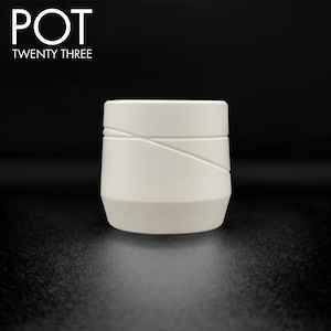 May include: A white ceramic pot with a geometric design. The pot has a cylindrical shape with angled lines across the surface. The text "POT TWENTY THREE" is above the pot.