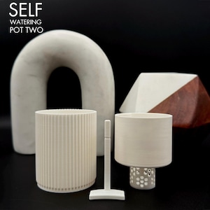 May include: A collection of modern, minimalist planters and decorative objects. The image features a large, arched sculpture, two cylindrical pots, a small tool, and a geometric wooden piece. The text "SELF WATERING POT TWO" is at the top.