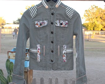 Chaqueta militar reciclada con detalles florales verde oliva y ribete de rayas.