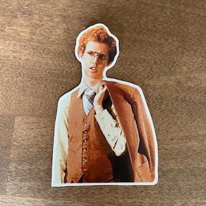 May include: A sticker of a man with red hair wearing a brown vest, a white shirt, and a brown jacket. He is wearing glasses and has a serious expression on his face.