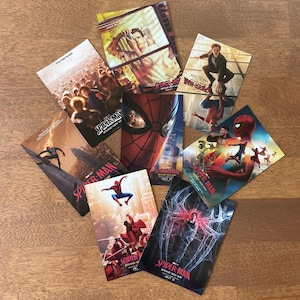 May include: A collection of eight rectangular Spider-Man movie posters featuring various scenes, including a close-up of the mask, city skylines, and action poses. Each poster displays the Spider-Man title and release date text in red and white.