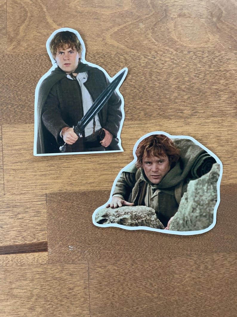 May include: Two stickers featuring images of a character from the Lord of the Rings movie. The first sticker shows the character holding a sword. The second sticker shows the character climbing a rock.