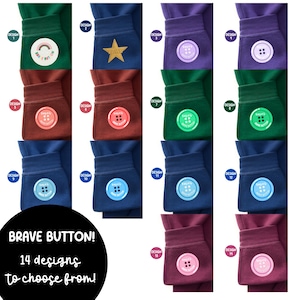 May include: A selection of fourteen Brave Button designs, each attached to a fabric cuff. The buttons feature diverse colours and patterns, including a rainbow, star, and various button designs. The text "BRAVE BUTTON! 14 designs to choose from!" is also visible.