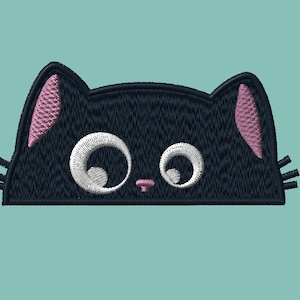 Può includere: Viso di gatto nero ricamato con orecchie rosa e occhi bianchi. Il gatto guarda direttamente lo spettatore.