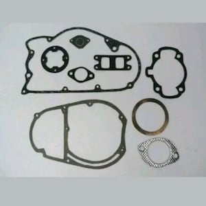 May include: A set of black engine gaskets in diverse shapes, including circles, rectangles, and irregular outlines. The gaskets are displayed against a light backdrop, highlighting their detailed forms and textures. Suitable for automotive maintenance.