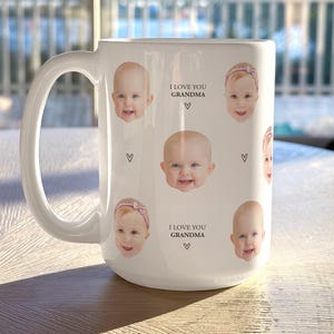May include: White ceramic mug featuring multiple baby photos and the text "I LOVE YOU GRANDMA" with heart symbols. The mug has a large handle and is likely used for beverages.