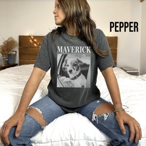 May include: Dark gray t-shirt with the word "MAVERICK" above a black and white image of a dog. The word "PEPPER" is printed in large black letters on the upper right side of the shirt.
