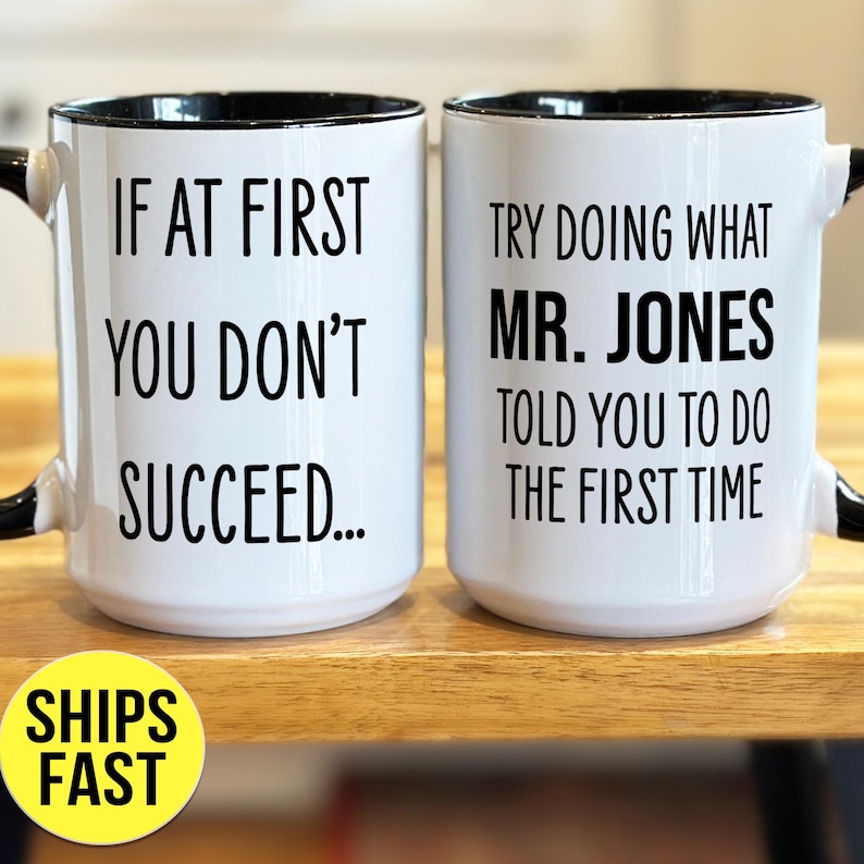 May include: Two white ceramic mugs with black rims and handles. One mug reads "IF AT FIRST YOU DON'T SUCCEED..." and the other says "TRY DOING WHAT MR. JONES TOLD YOU TO DO THE FIRST TIME."