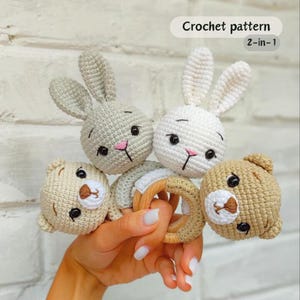 Puede incluir: Patrón de ganchillo para juguetes para bebés dos en uno. La imagen muestra dos cabezas de conejito de ganchillo, dos cabezas de oso de ganchillo y un anillo de madera. Los conejitos son blancos y grises, y los osos son marrones. Los conejitos tienen narices rosas y ojos negros.