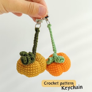 May include: Two crochet pumpkin keychains, one yellow and one orange, with green stems and leaves. The keychains are attached to silver clasps. The text "Crochet pattern Keychain" is in a yellow rectangle.