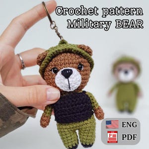 May include: Crochet pattern for a military bear amigurumi toy. The bear is brown with a green hat and vest. The pattern is available in English and PDF format.