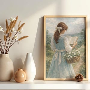May include: A framed print depicts a woman in a blue dress reading a book while carrying a basket of flowers. The print is displayed on a white shelf alongside three vases with dried flowers and a decorative pinecone.