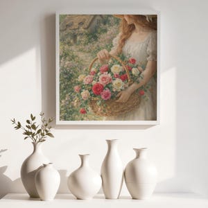 May include: A framed print depicts a woman in a white dress holding a woven basket overflowing with pink and white roses. Below, five white ceramic vases of varying shapes sit on a white surface, with a sprig of greenery in the leftmost vase.