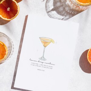 May include: A printable recipe card for a lemon drop martini cocktail. The card features a watercolour illustration of a martini glass with a lemon wedge garnish. The recipe calls for 3 fluid ounces of vodka, 1 fluid ounce of triple sec liqueur, 1/2 fluid ounce of lemon juice, and 1/2 fluid ounce of simple syrup. Garnish with a lemon wedge.