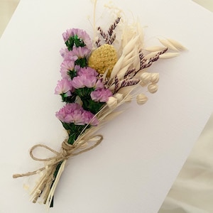 May include: A small bouquet of dried flowers tied with twine. The bouquet includes purple statice, yellow billy buttons, and dried grasses.