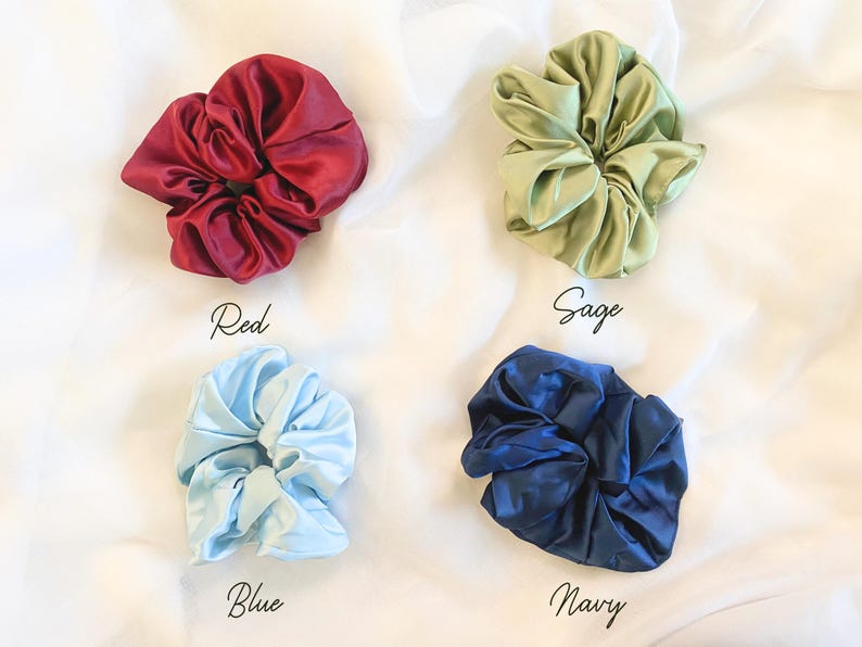 May include: Four satin scrunchies in different colors: red, sage green, blue, and navy.