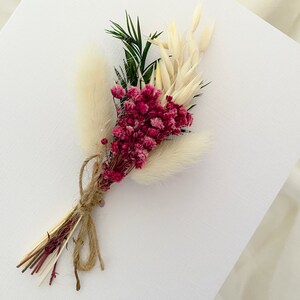 May include: A small bouquet of dried flowers with pink and white blooms, tied with twine.