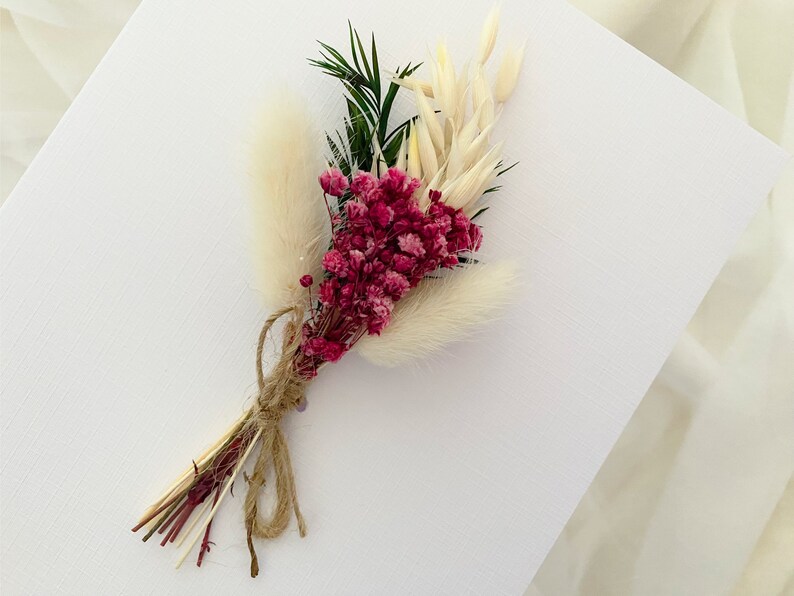 May include: A small bouquet of dried flowers with pink and white blooms, tied with twine.