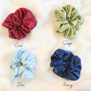 May include: Four satin scrunchies in different colors: red, sage green, blue, and navy.