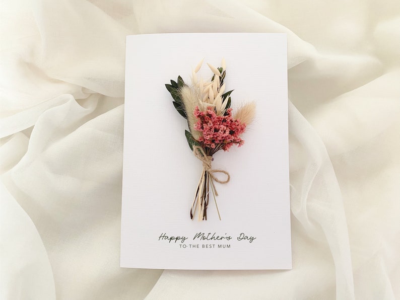 May include: A white card with a bouquet of dried flowers and the text "Happy Mother's Day to the Best Mum".