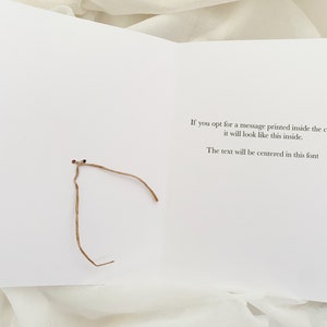 May include: A white card with a brown string tied around it. The card has text that reads: "If you opt for a message printed inside the card it will look like this inside. The text will be centered in this font."