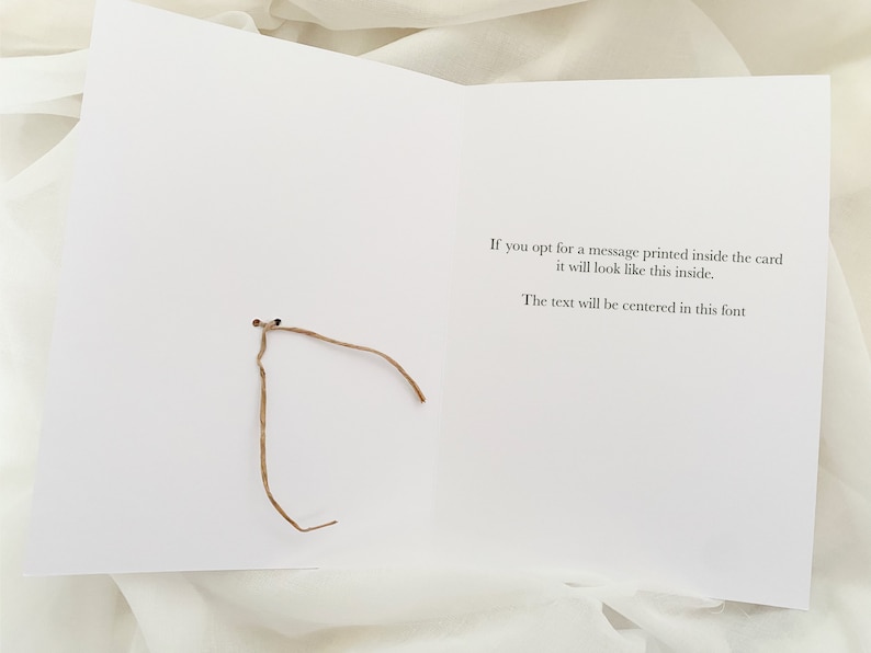 May include: A white card with a brown string tied around it. The card has text that reads: "If you opt for a message printed inside the card it will look like this inside. The text will be centered in this font."
