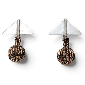 May include: A pair of earrings featuring a silver-toned triangular top piece with a vertical bar attachment. Suspended from each bar is a spherical charm crafted from small, metallic bronze-colored beads arranged in a textured, grid-like pattern.